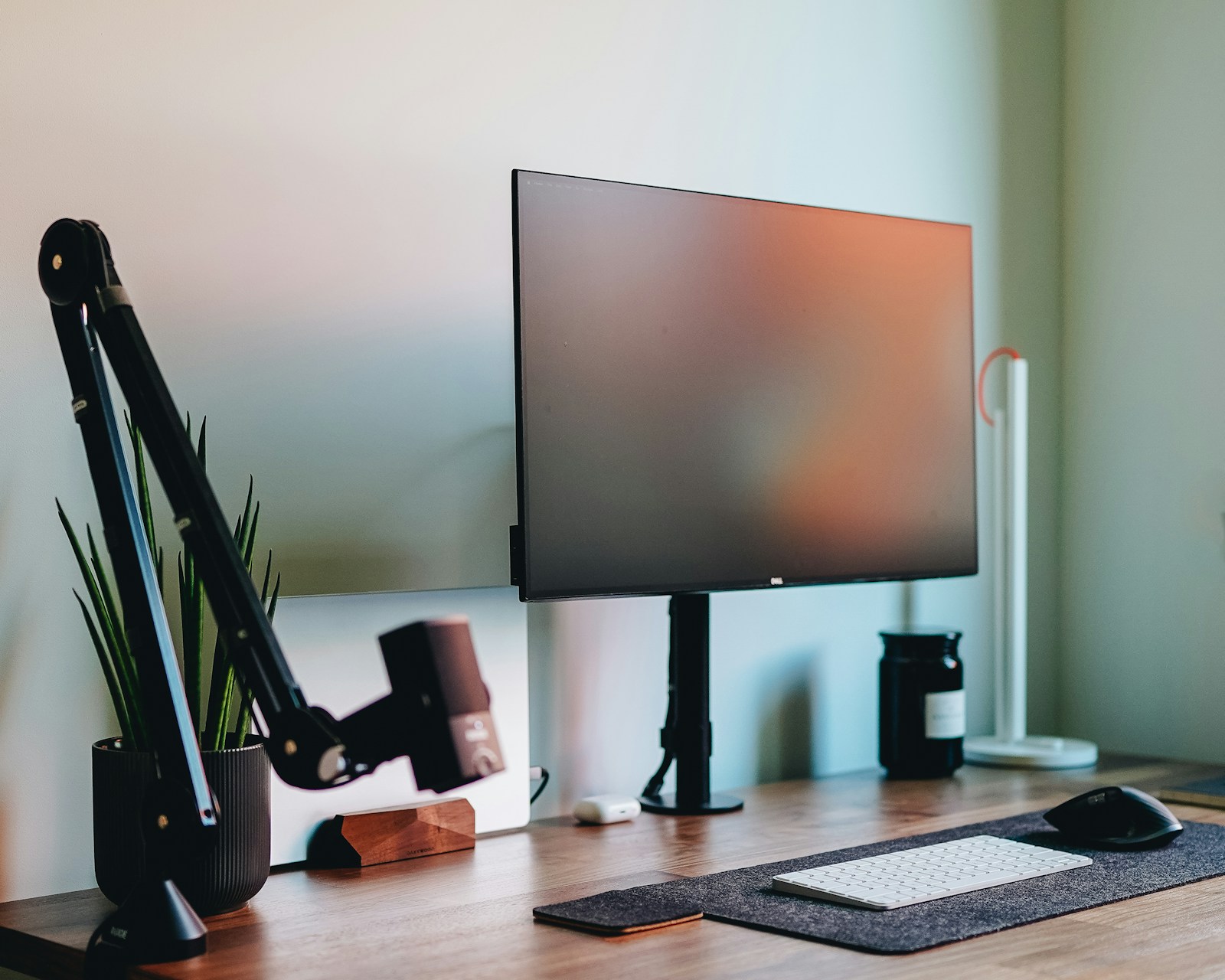 A desktop workspace with a monitor, keyboard and a walnut desk.
